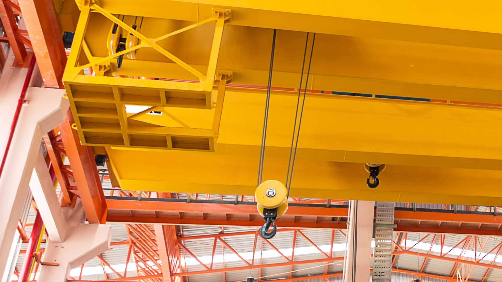 Overhead yellow industrial crane with a pulley and hook system