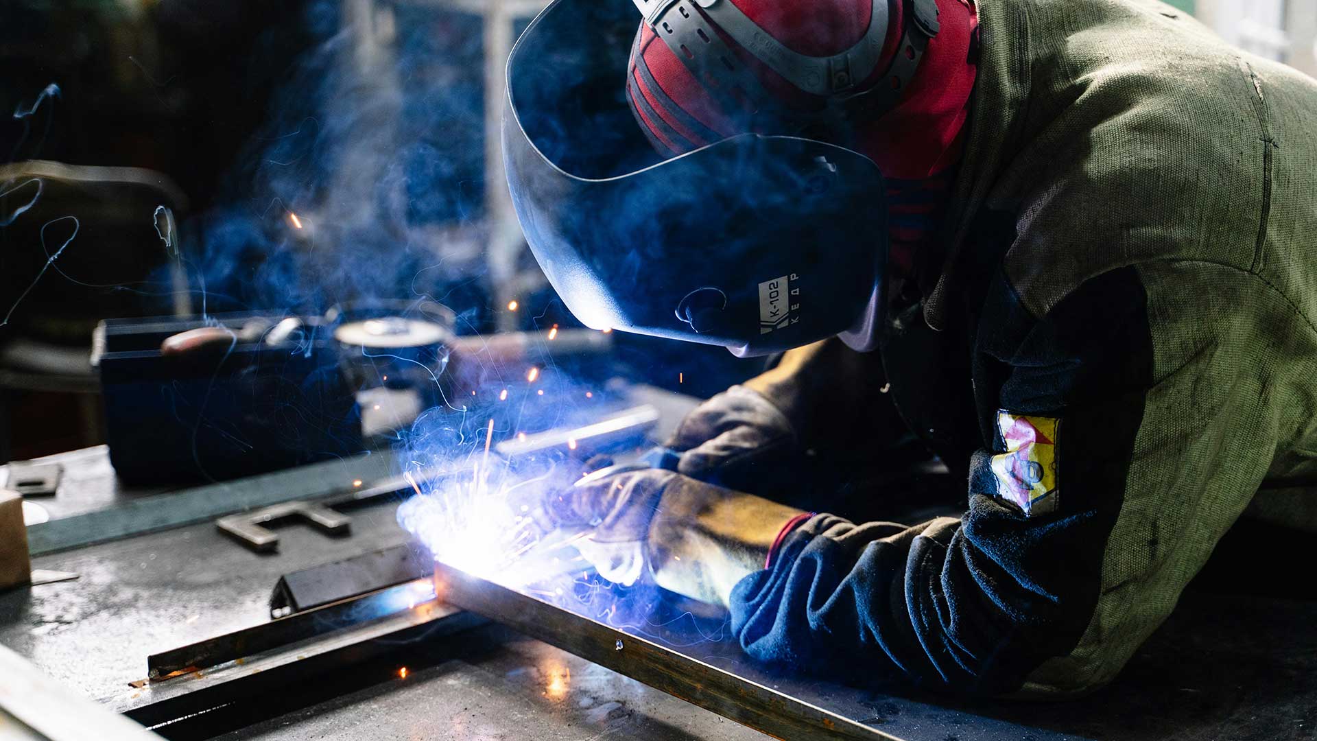 Welder welding steel while wearing protective gear.