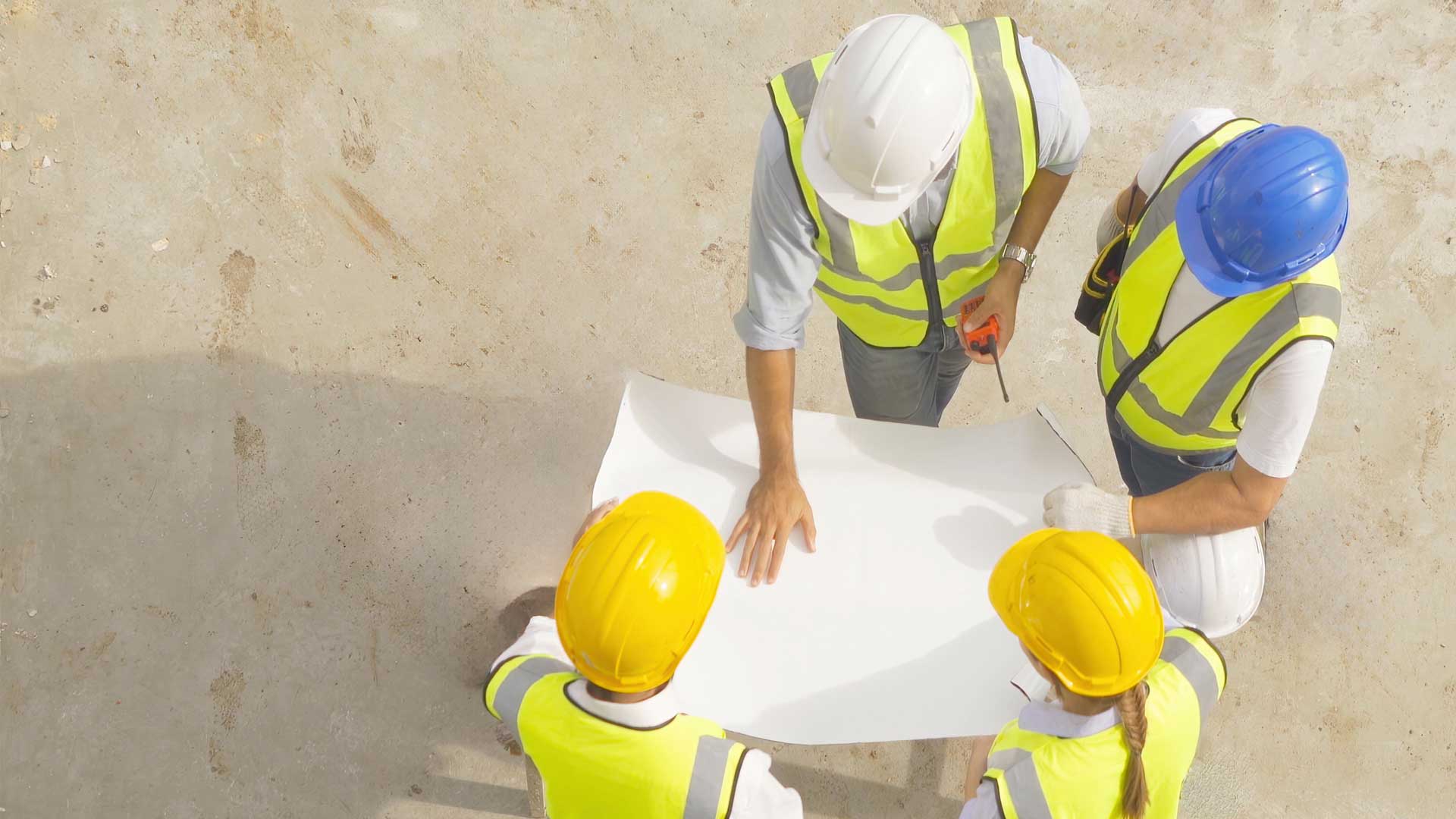 Workers wearing PPE gathered around and reviewing plans.