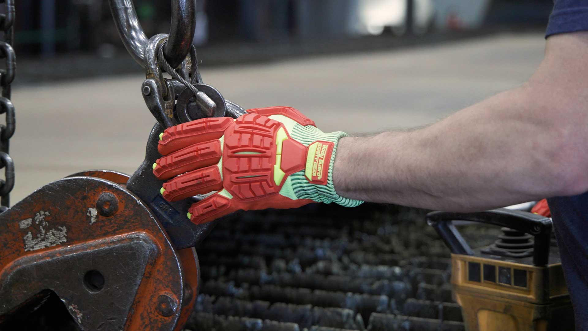 Worker wearing protective gloves while securing a heavy hook and chain.