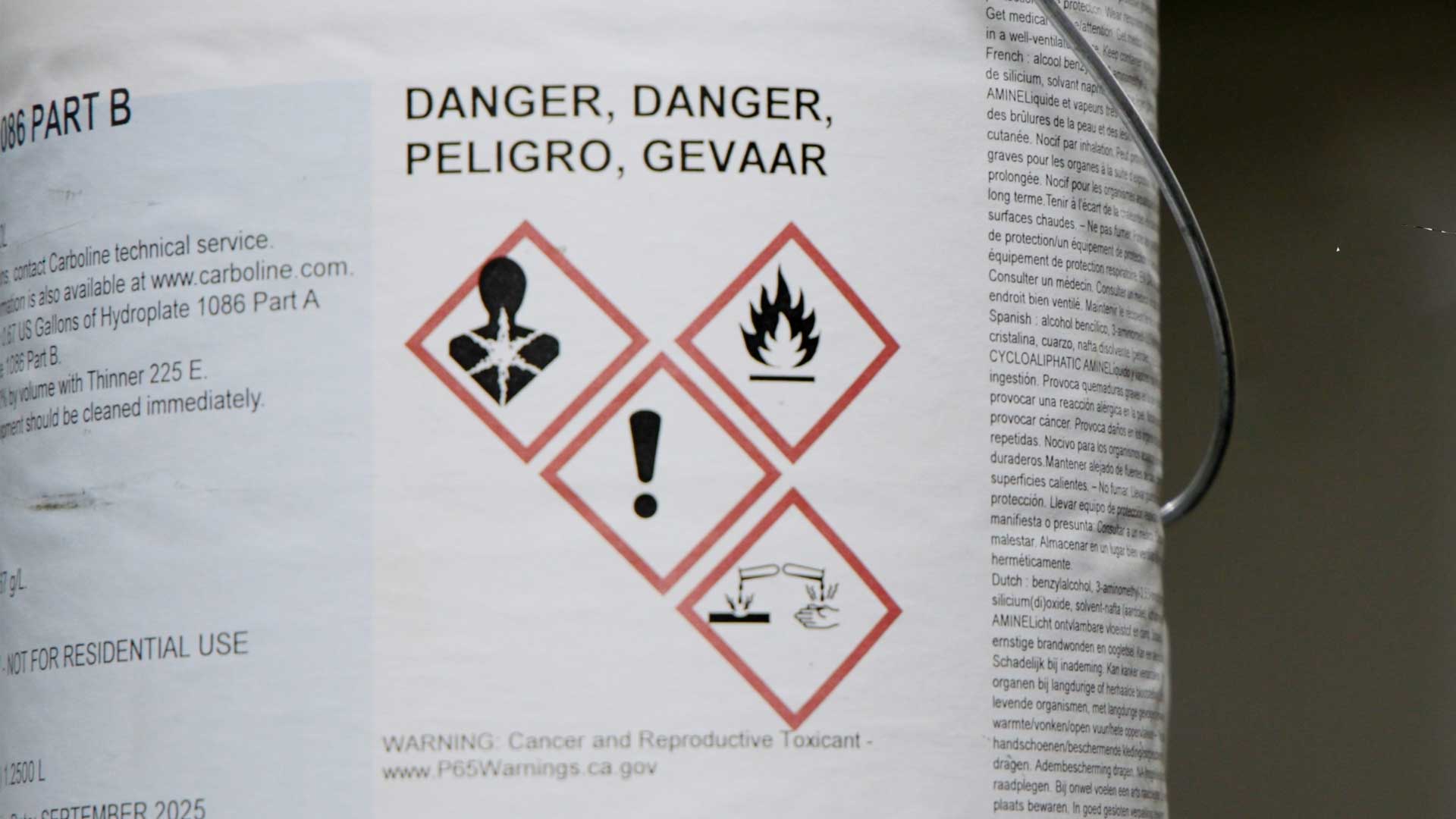 Chemical container with hazard symbols for health, flammability, irritation, and corrosion.
