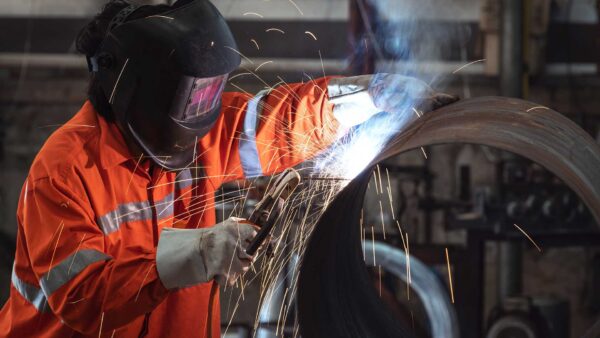 Welder with a protective face mask welding steel pipe