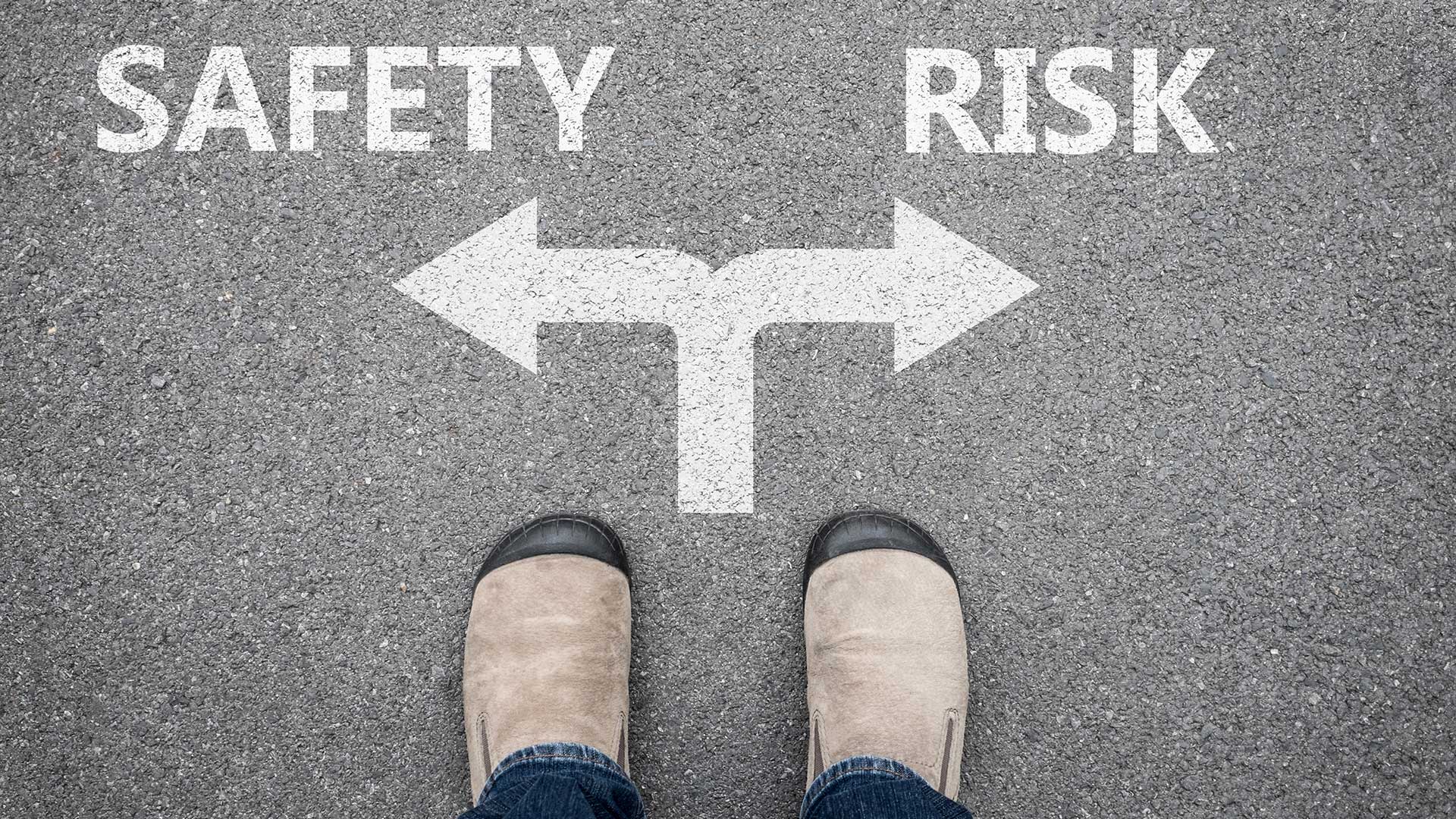 Person standing at a crossroads with arrows pointing to 'Safety' on the left and 'Risk' on the right, symbolizing a decision-making moment.