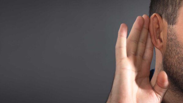 Person holding a hand to their ear as if listening closely.