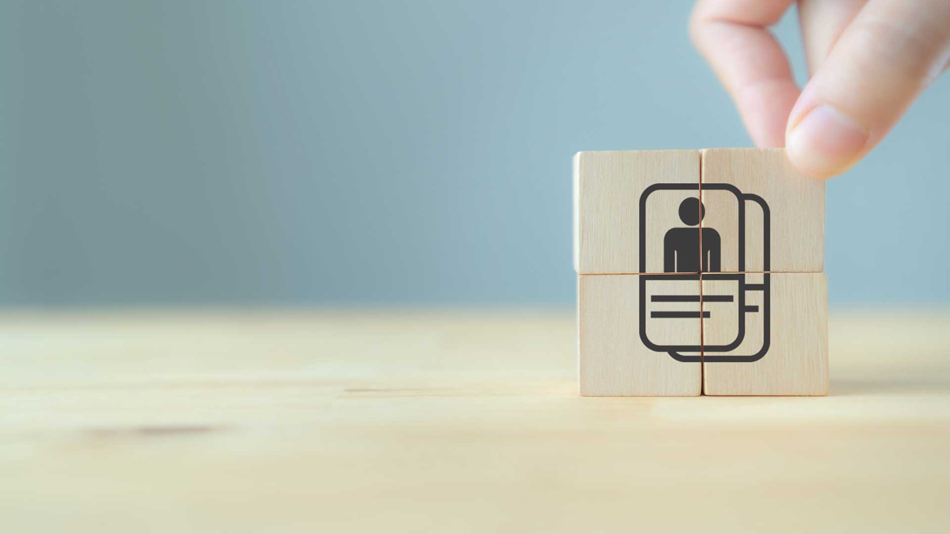 Hand placing wooden blocks with a customer icon to represent defining an ideal customer profile.