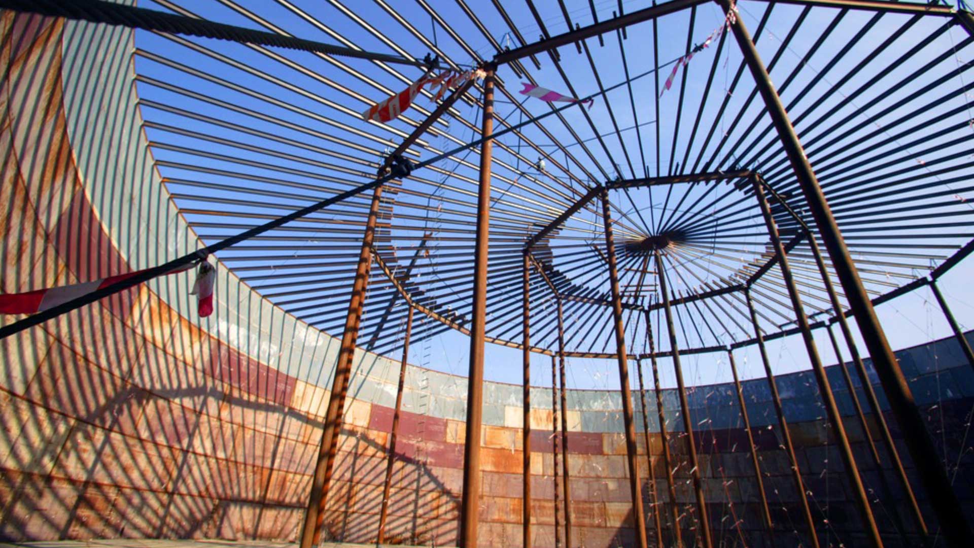 Steel storage tank roof under construction with radial rafters and center compression ring during field erection.