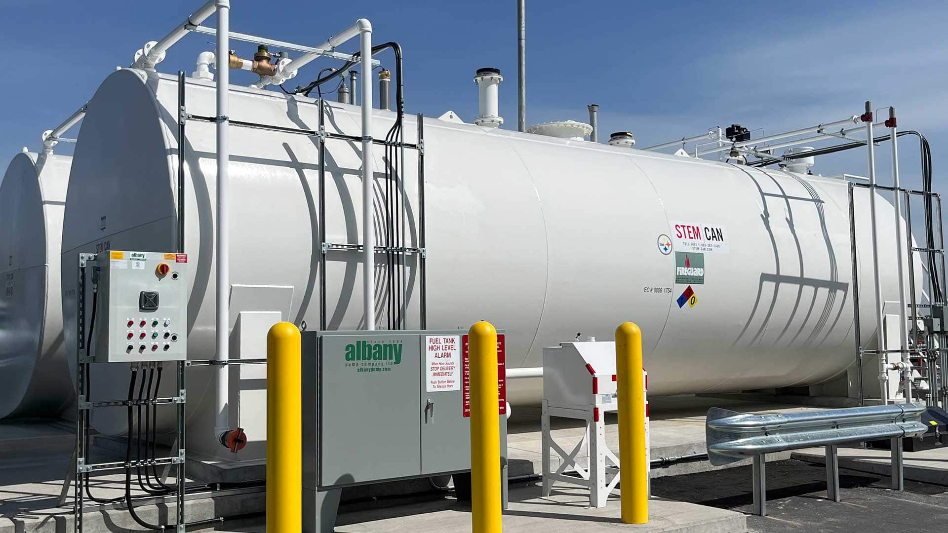 STEM-CAN FIREGUARD® double-wall steel fuel storage tank with external piping, control panels, and safety bollards installed on a concrete pad.