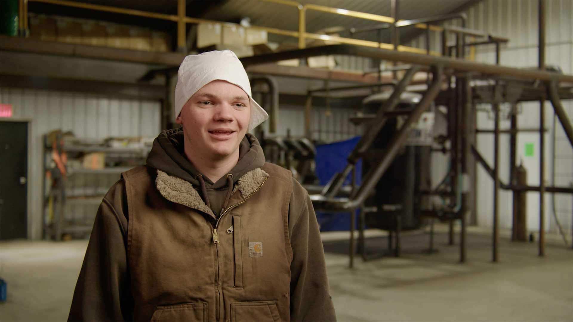 Young man speaking during an interview inside a welding and fabrication training facility.