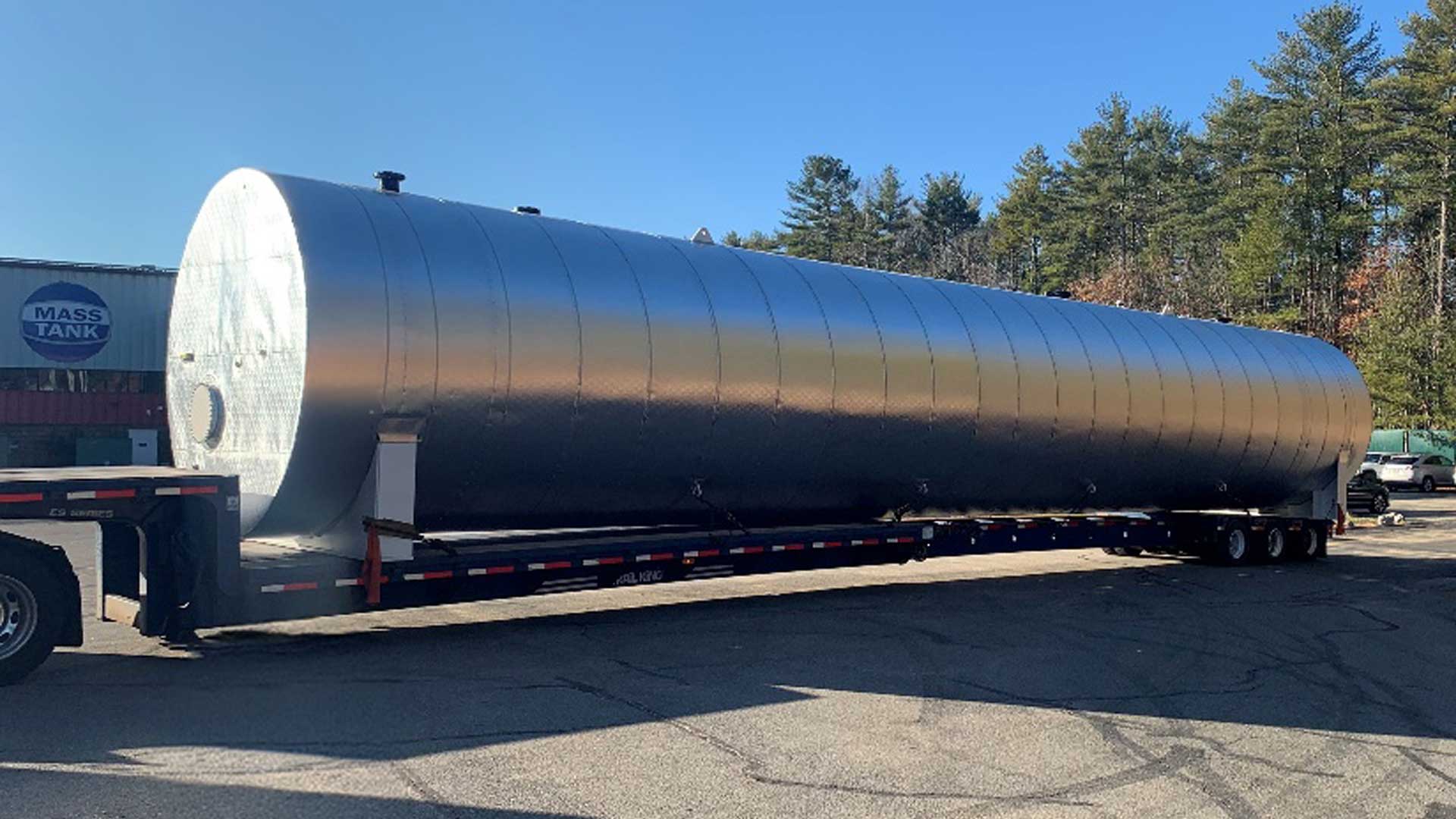 Large insulated steel storage tank secured on a flatbed trailer for transport.