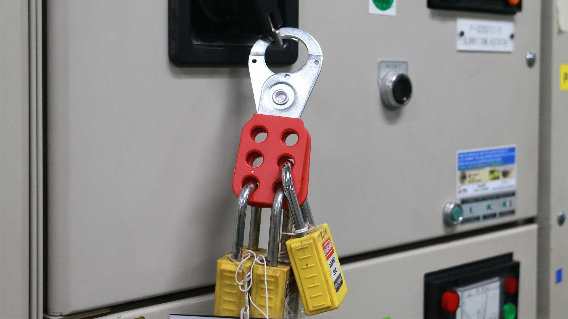 Lockout/tagout device with multiple safety locks attached to an industrial electrical control cabinet.