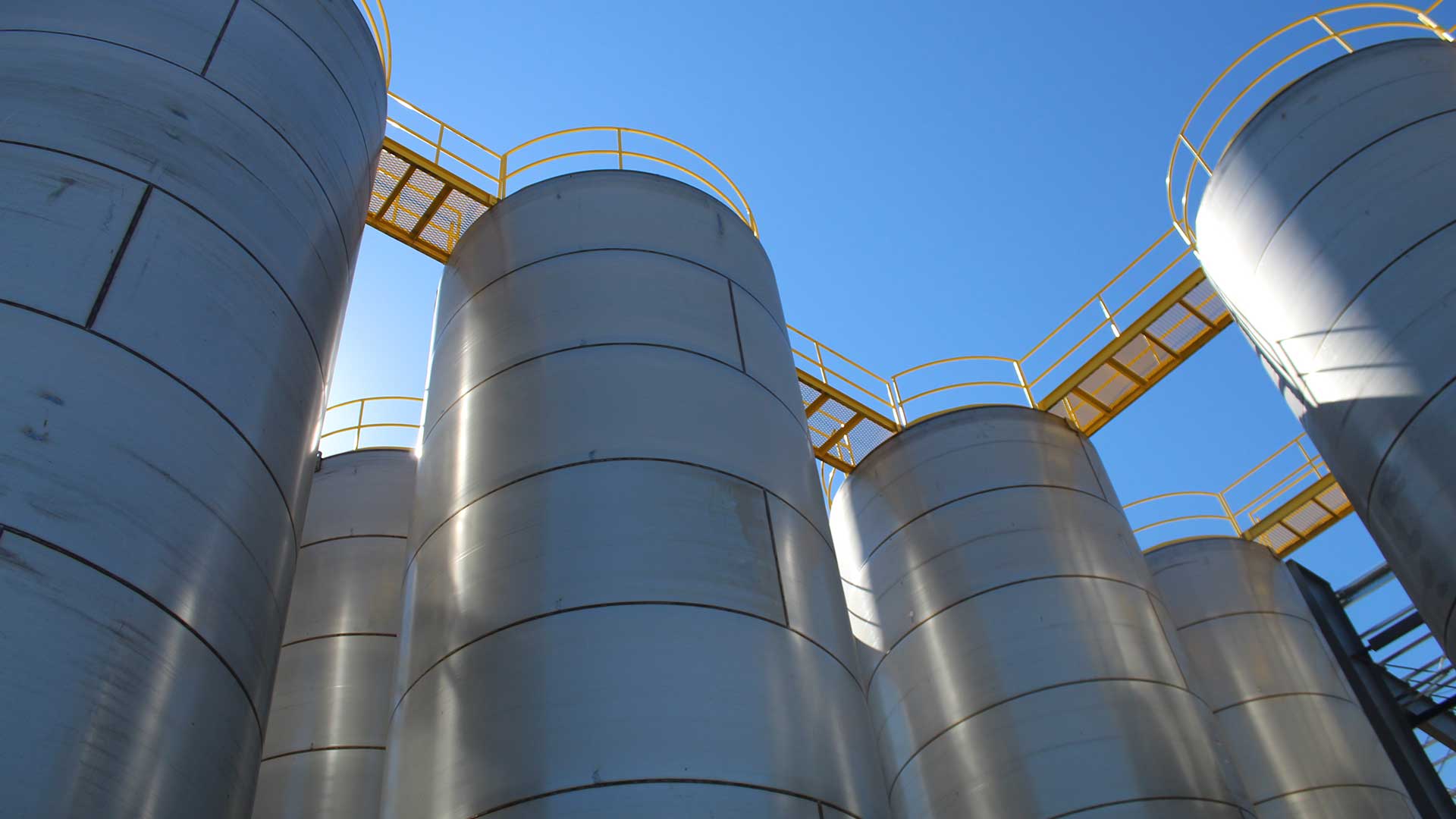 Field-erected steel storage tanks with yellow access platforms and walkways.