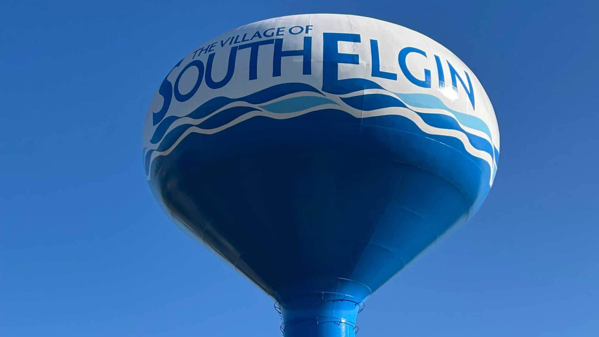 Elevated steel water storage tank for the Village of South Elgin against a clear blue sky.