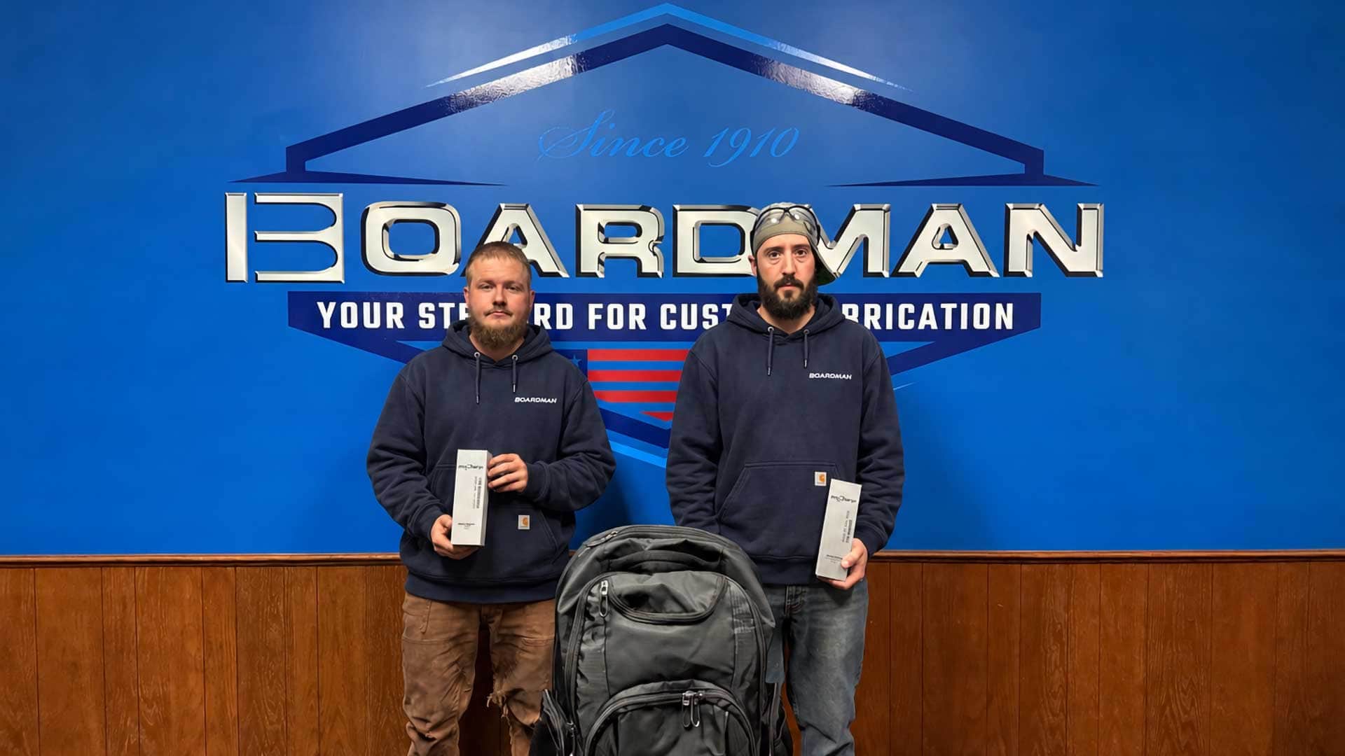 Max Higgins, left, and Chris Fralia hold their 2026 Weld of the Year awards in front of a Boardman sign.
