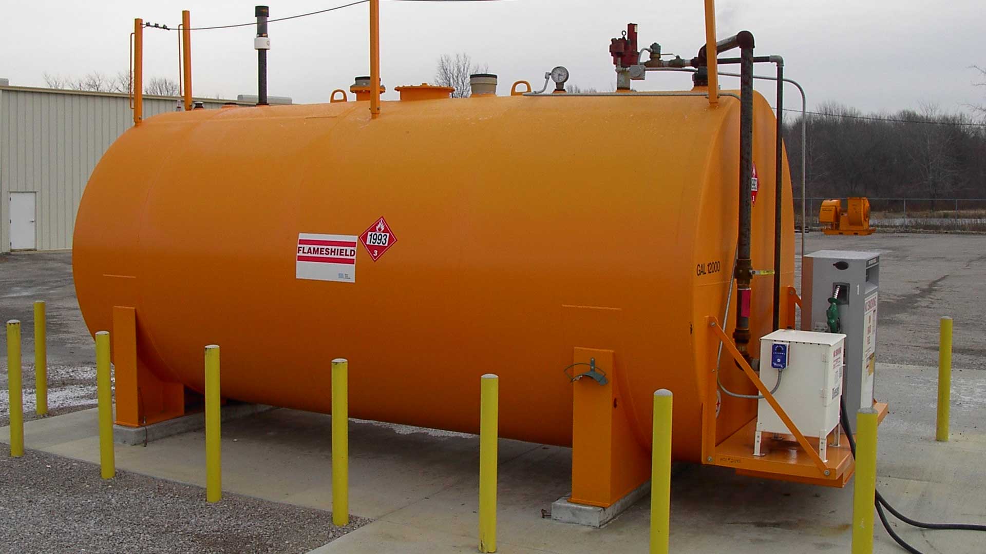 Orange FLAMESHIELD® aboveground fuel storage tank with dispensing equipment at a commercial fueling site.