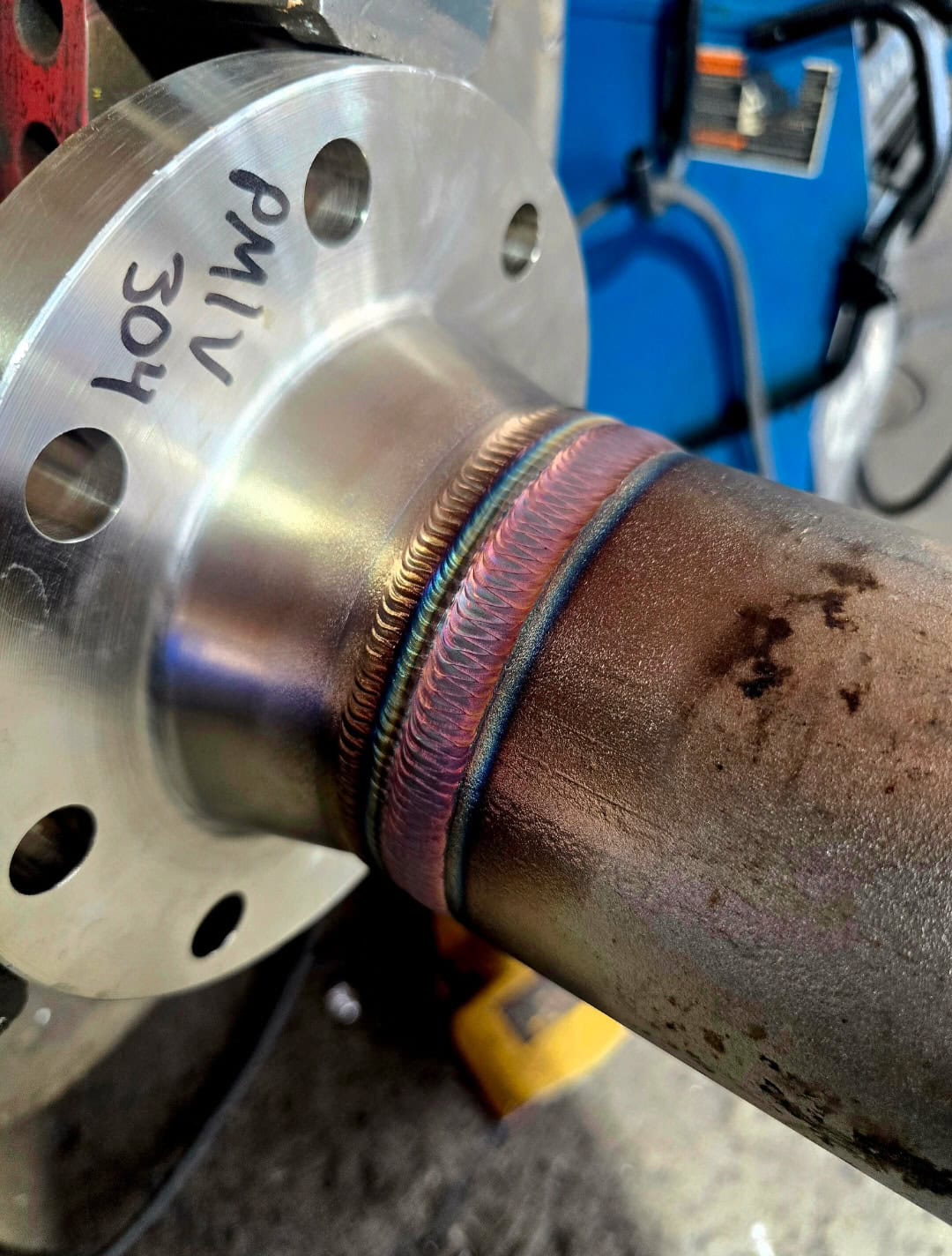 Close-up of a welded stainless steel drain line connected to a flange for a pressure vessel application.