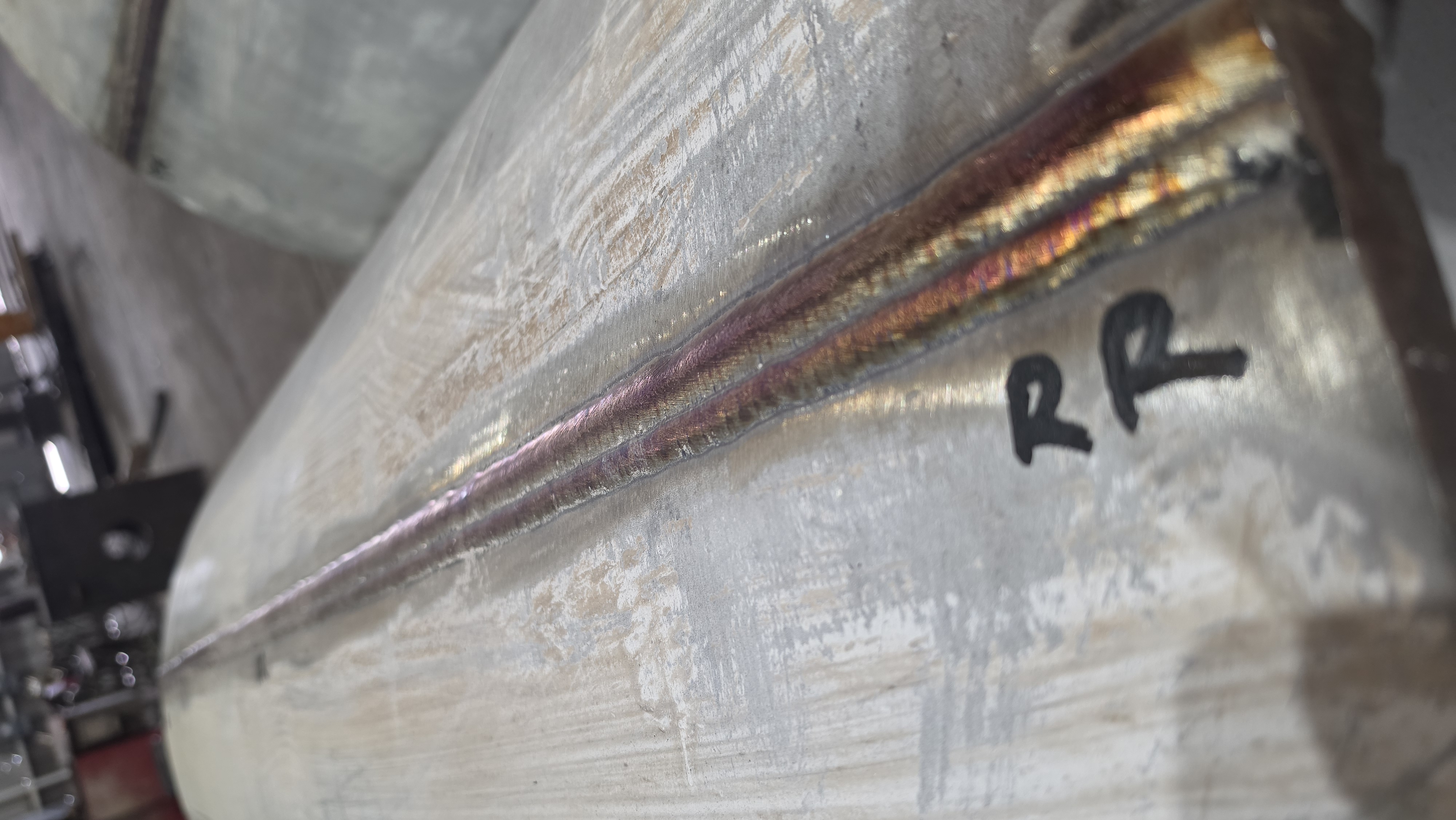 Close-up of a welded stainless steel drain line connected to a flange for a pressure vessel application.